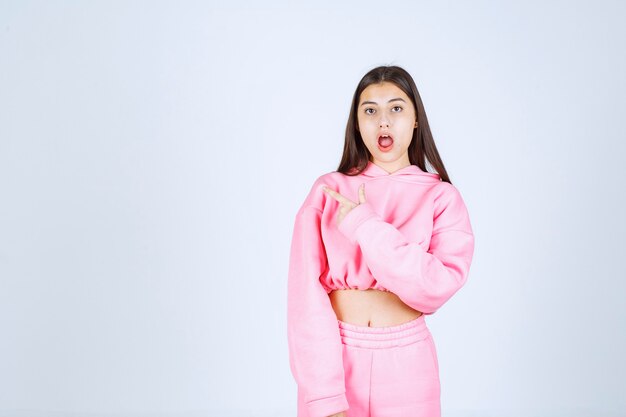 Girl in pink pajamas pointing at something on the left