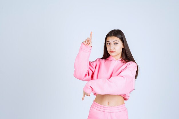 Girl in pink pajamas pointing to somewhere. 