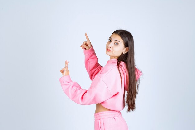 Girl in pink pajamas pointing up