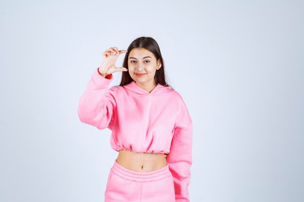 Девушка в розовой пижаме показывает примерное количество или размер товара