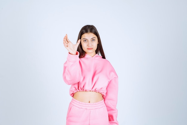 Girl in pink pajamas showing the estimated amount or size of a product