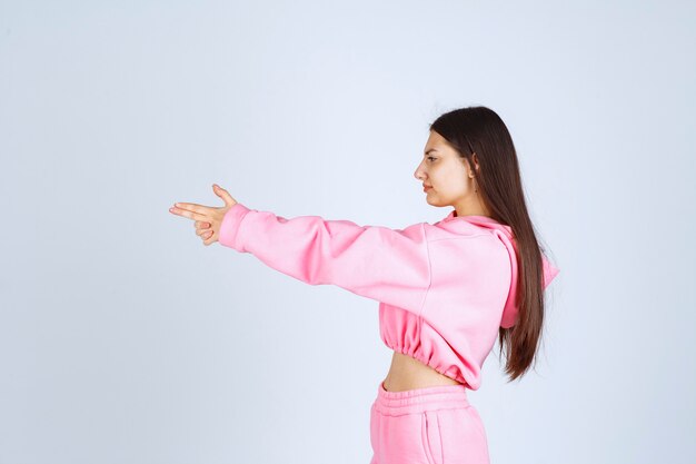 Girl in pink pajamas showing gun sign in the hand