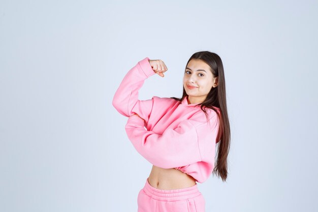 Girl in pink pajamas showing her fist and feeling powerful. 