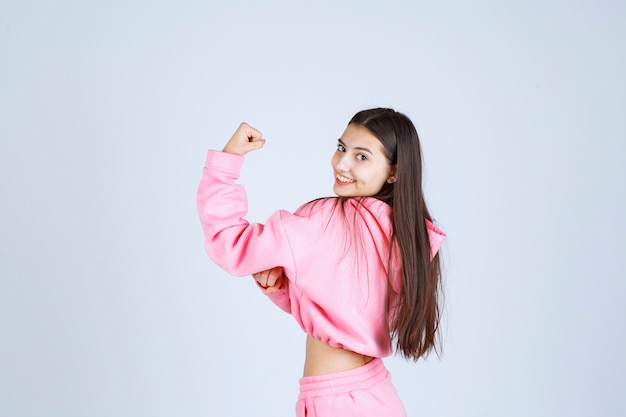 Girl in pink pajamas showing her fist and feeling powerful. 