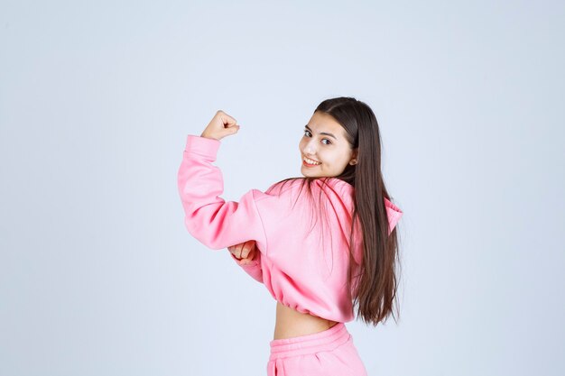 Девушка в розовой пижаме показывает кулак и чувствует себя сильной.