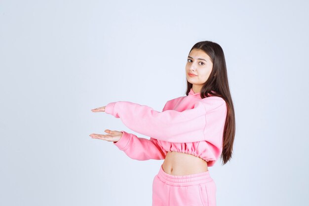 Girl in pink pajamas showing the size of an object