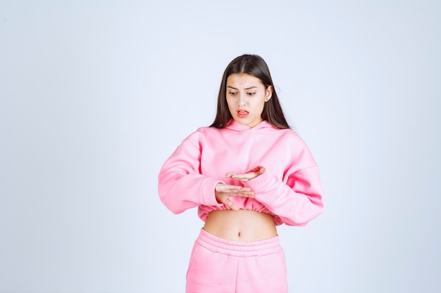 Free photo girl in pink pajamas showing the size of an object