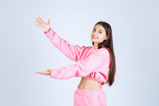 Girl in pink pajamas showing the size of an object