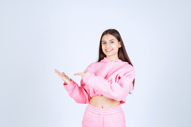 Девушка в розовой пижаме показывает что-то в руке