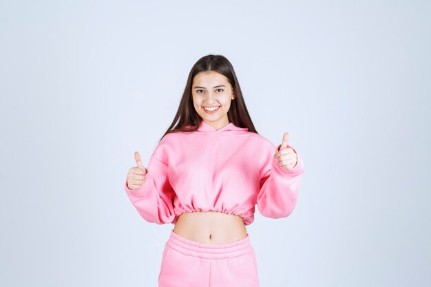 Girl in pink pajamas smiling and enjoying something. 