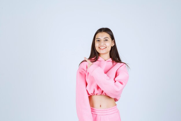 Girl in pink pajamas smiling and showing back side. 