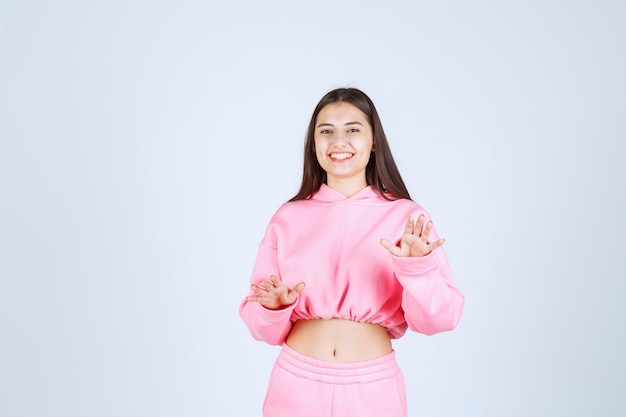 Ragazza in pigiama rosa che ferma qualcosa