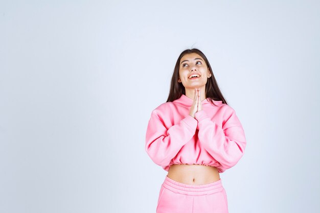 Девушка в розовой пижаме объединяет руки и молится