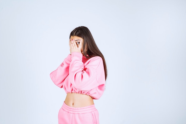 Free photo girl in pink pijamas looking through her fingers