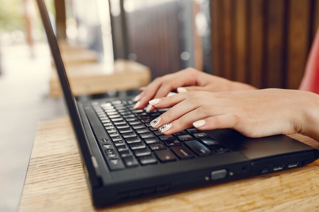 Girl in a pink shirt sitting at the table and use the laptop