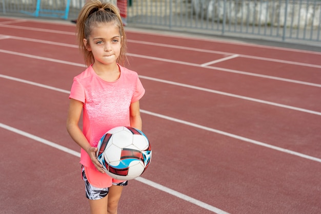 サッカーを保持しているピンクのtシャツの女の子