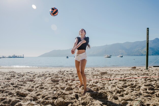 Девушка играет в пляжный волейбол