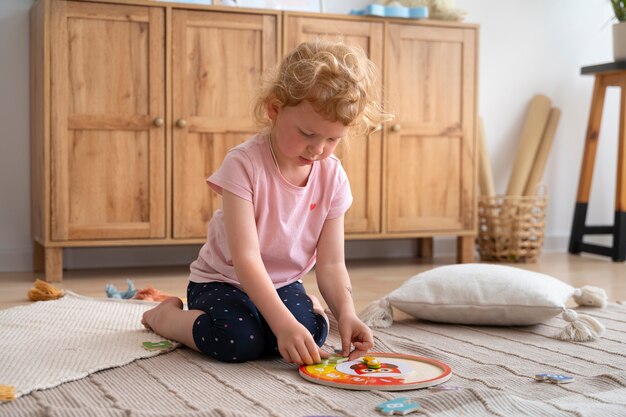 Free photo girl playing on floor with puzzle side view