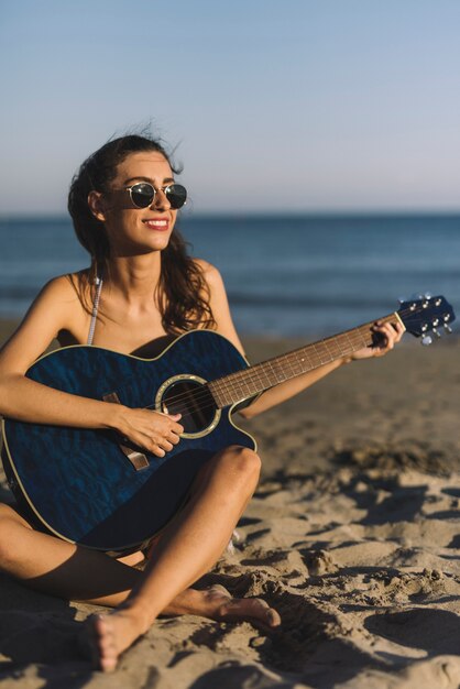 Girl playing guitar at the beach