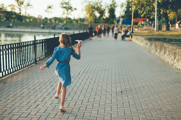 Free photo girl playing, running with toy paper airplane