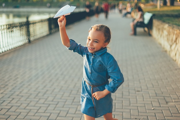 Girl playing, running with toy paper airplane