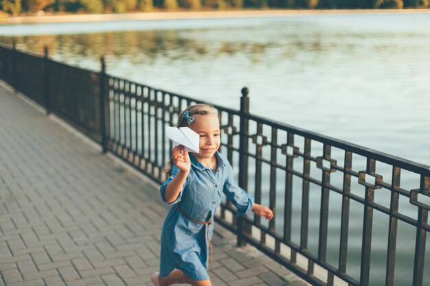 Girl playing, running with toy paper airplane