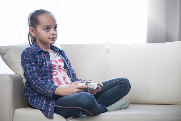 Бесплатное фото Девушка играет в видеоигру на диване