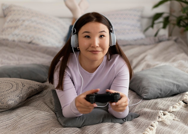 ベッドのフルショットでビデオゲームをしている女の子