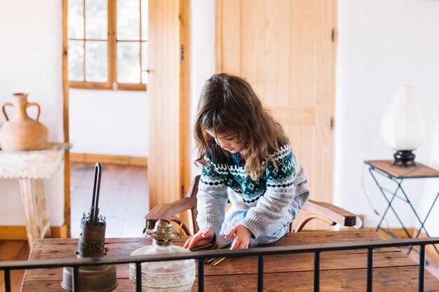 girl playing with plastic sticks on wooden desk
