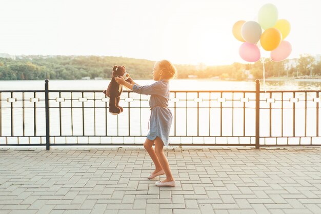 Girl playing with a tedy bear outdoors