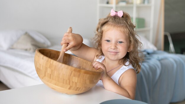 Девушка играет с деревянной миской и ложкой