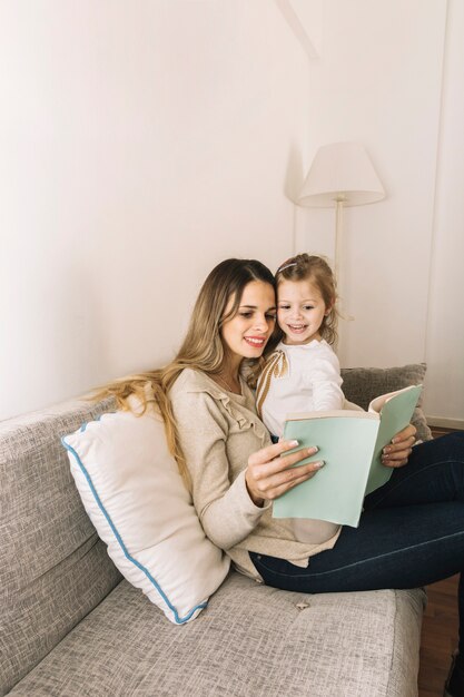 Girl pointing at book while reading with mom