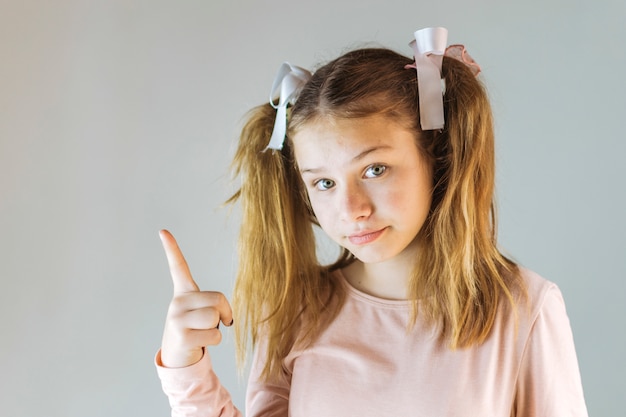 Girl pointing up on grey background