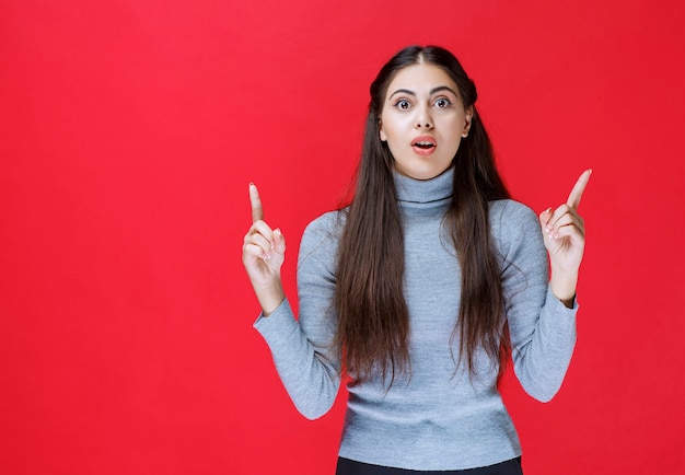 Girl pointing up and showing something above.