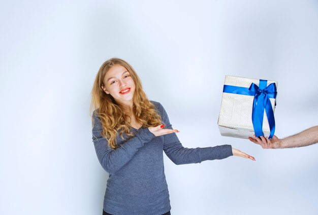 그녀에 게 제안하는 흰색 파란색 선물 상자를 가리키는 소녀.