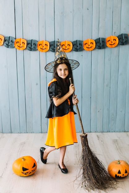 Girl in pointy hat standing with broom