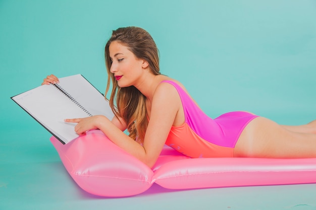 Free photo girl on pool mattress pointing at folder