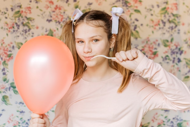 Girl popping balloon with fork looking at camera