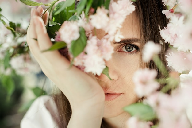 Foto gratuita il ritratto della ragazza fra i fiori di sakura si chiude su