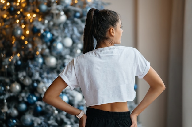 Ragazza in posa sullo sfondo di decorazioni natalizie.