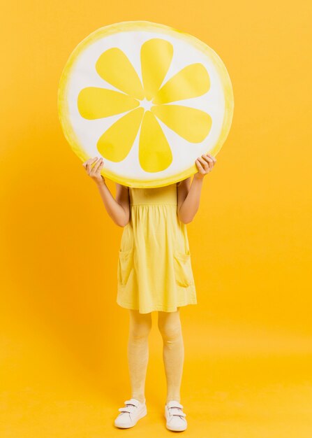 Девушка позирует, держа украшение ломтик лимона