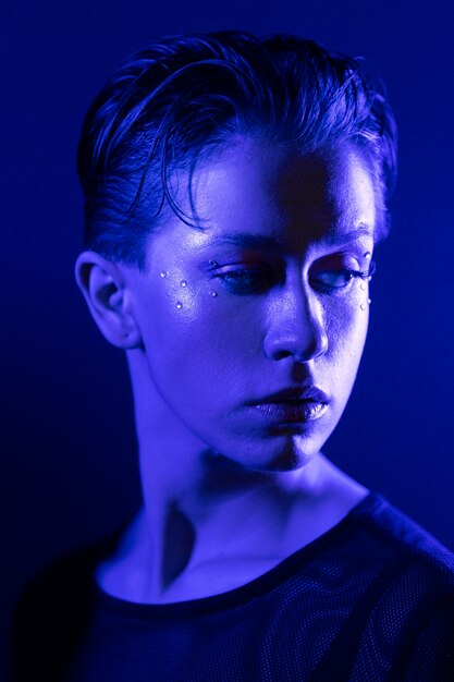 Бесплатное фото Девушка позирует с голубым светом, вид сбоку