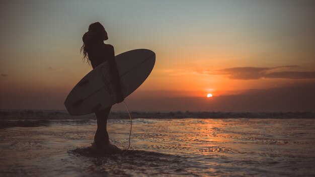 girl posing with a board at sunset