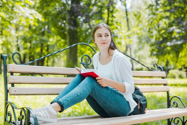 Девушка позирует с книгой на скамейке