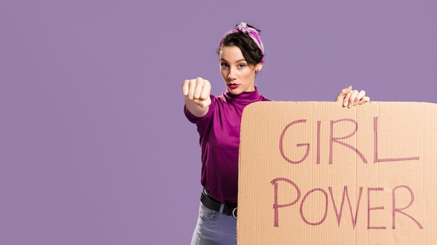 Free photo girl power lettering on cardboard and woman showing her fist