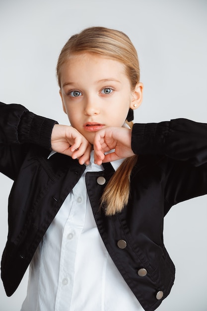 Free photo girl preparing for school after a long summer break. back to school. little female caucasian model posing in school's uniform on white studio background. childhood, education, holidays concept.