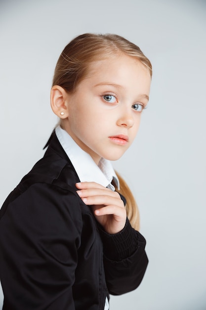 長い夏休みの後に学校の準備をしている女の子。学校に戻る。白い壁に学校の制服を着てポーズをとる小さな女性の白人モデル。子供の頃、教育、休日の概念。