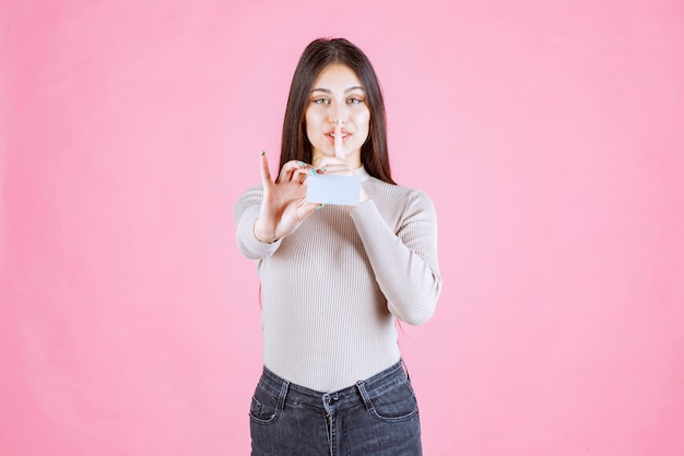 Girl presenting her business card and asking to keep silence