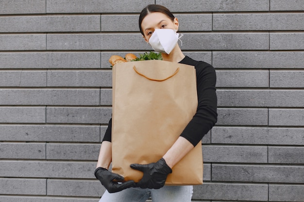 Girl in protective mask holds package with products