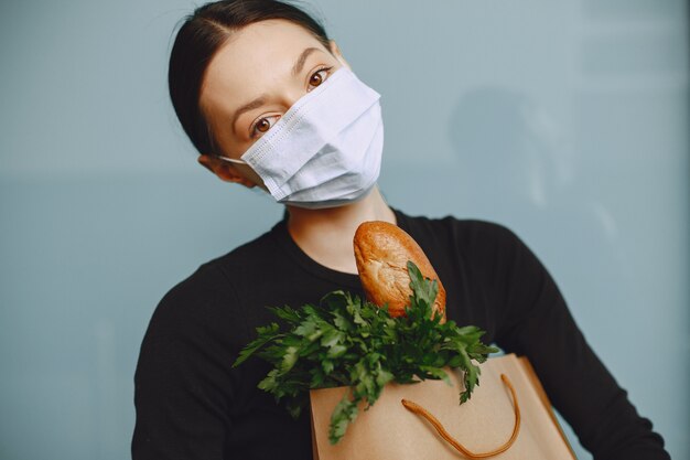 Girl in protective mask holds package with products